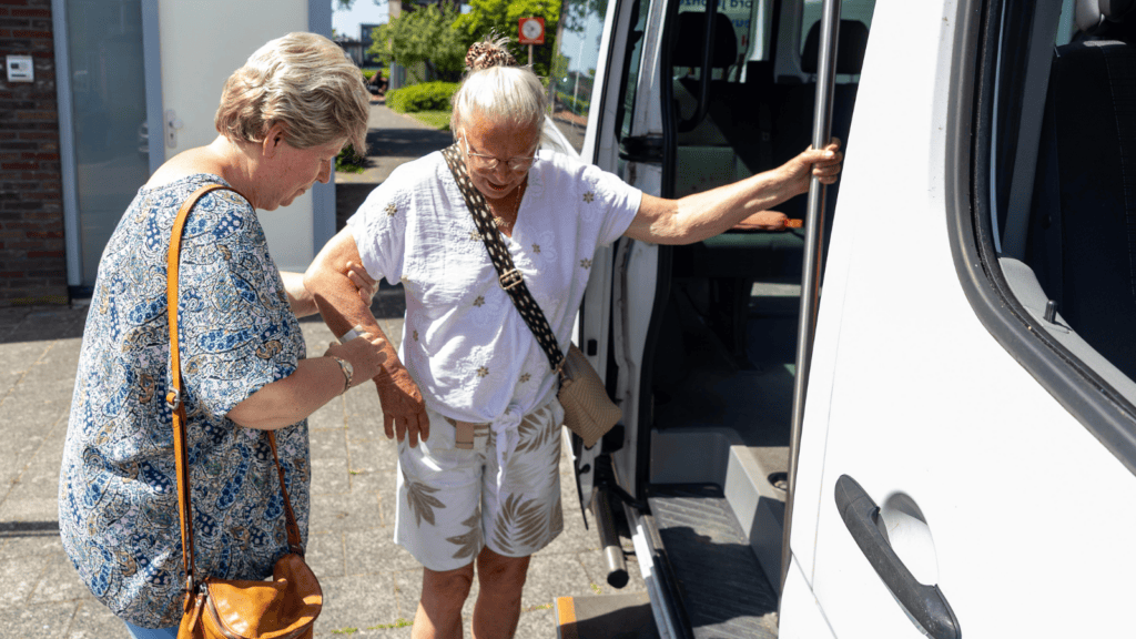 Aaf wordt geholpen bij het instappen in de PlusBus