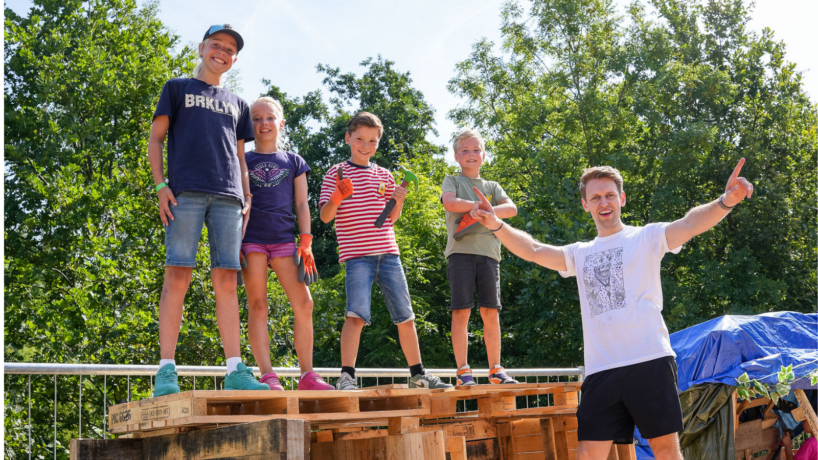 Jongeren en vrijwilliger op hun gebouwde hut tijdens Huttenbouw 2026